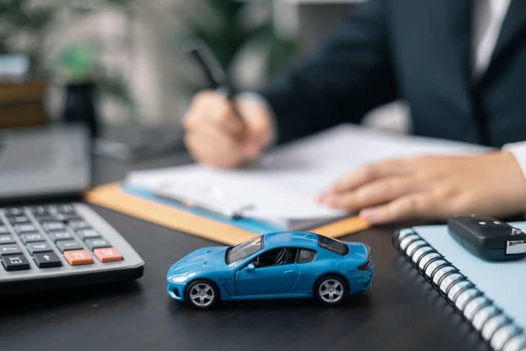 Imagem ilustrativa de miniatura de carro e prancheta para avaliação de custos