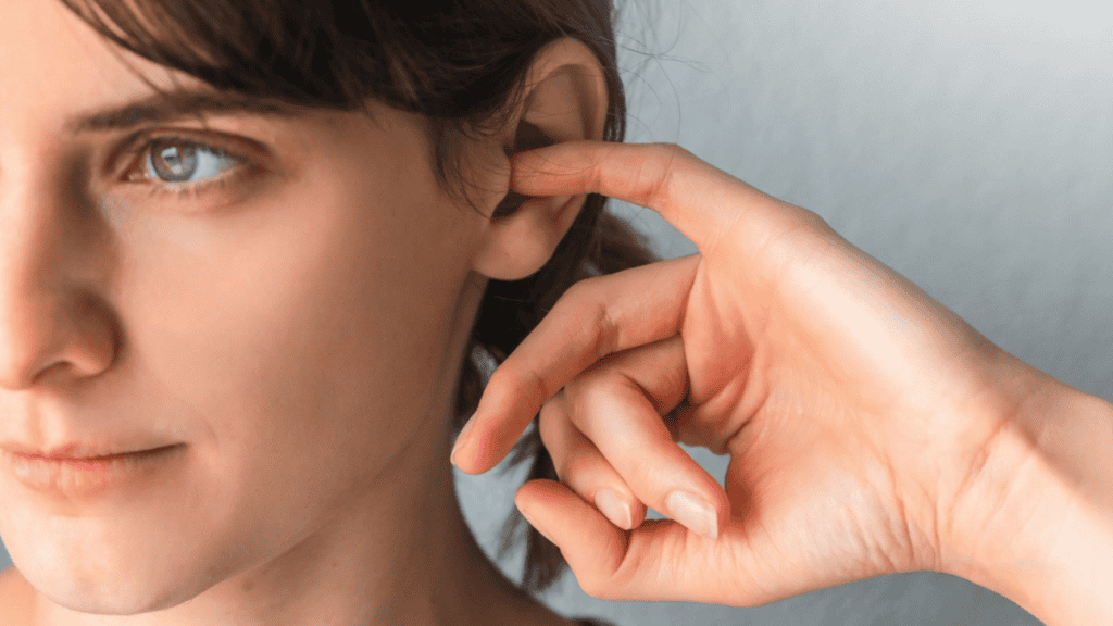 Mulher coçando o ouvido com o dedo