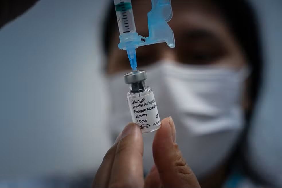 Pessoa manuseando um frasco de vacina da dengue
